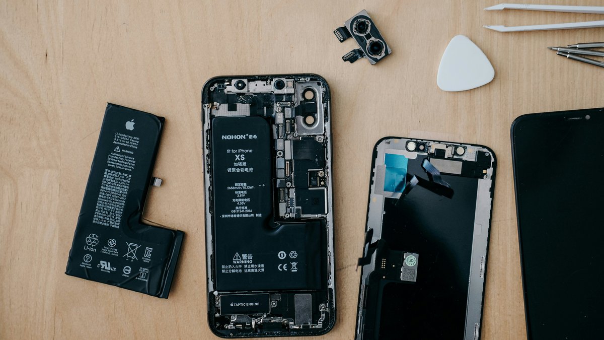 Linh kiện iPhone tháo rời gồm pin, vỏ máy, màn hình và cụm camera, minh họa quản lý linh kiện sửa chữa điện thoại